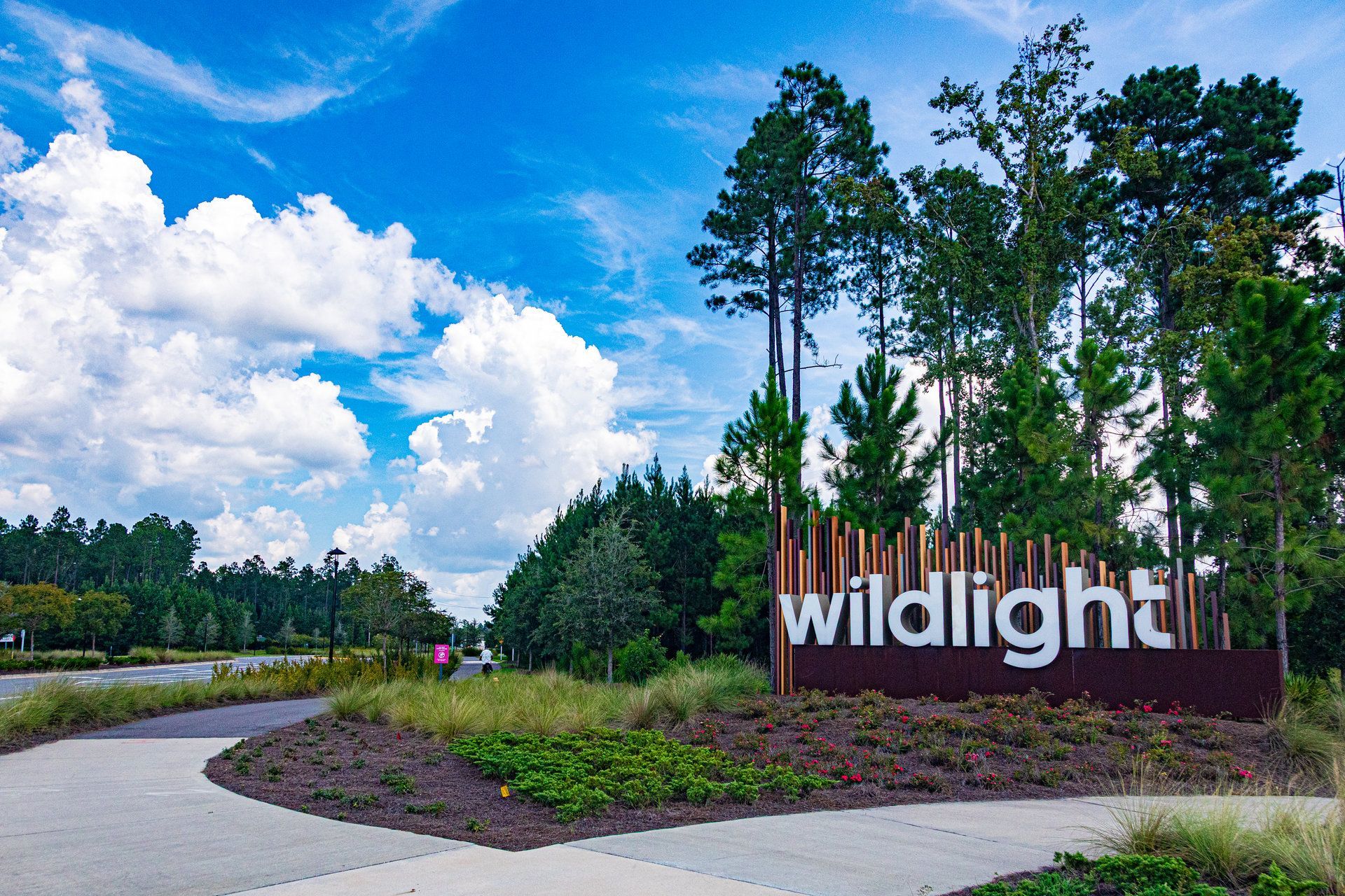 Wildlight entrance sign framed by tall pine trees and a blue sky in Wildlight, Florida.