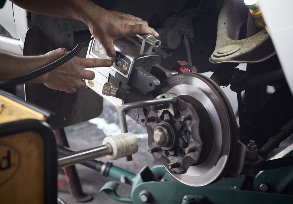 Mechanic Working on Car's Brakes, Using Tool on the Rotor and Caliper in a Repair Shop — Mike's Automotive in Edgeworth, NSW