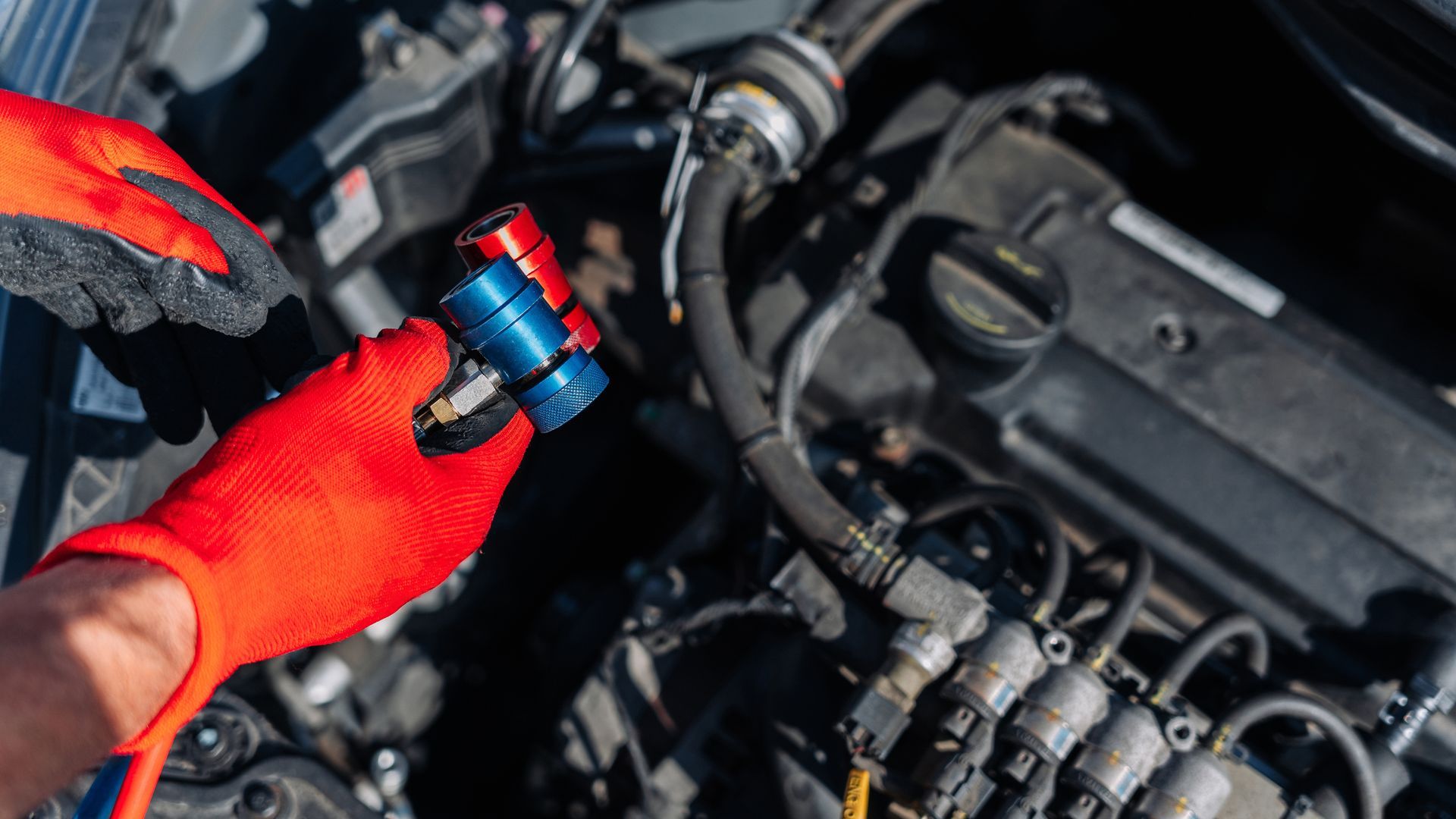 Hands Wearing Red Gloves Connecting a Blue and Red Tool to a Car Engine — Mike's Automotive in Edgeworth, NSW