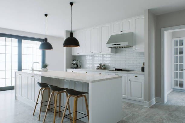 White kitchen with island, pendant lights, stools, and stainless steel range hood.