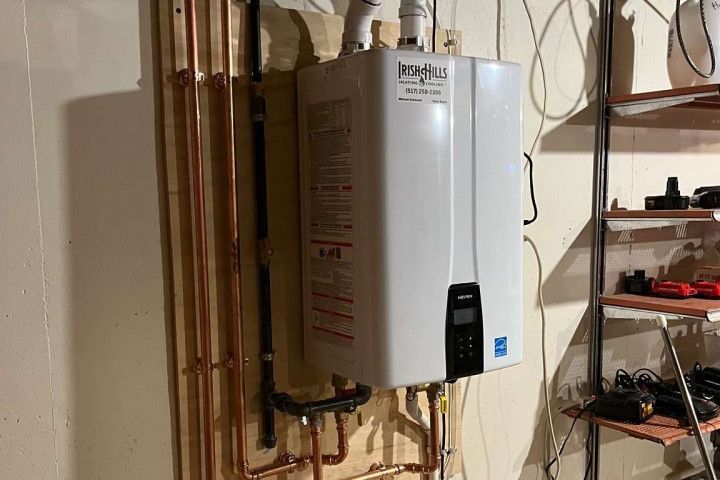 A white water heater is hanging on a wall next to copper pipes.