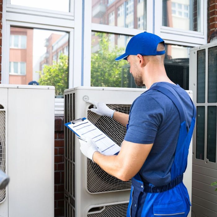 A man is standing in front of an exhaust holding a clipboard.