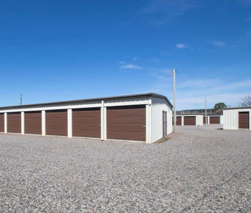 Brown roll-up storage unit doors along a gravel drive at StorMark Self Storage in Dardanelle, Arkansas
