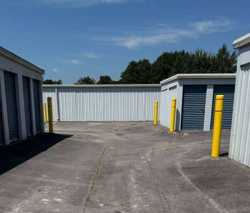 Drive-up storage units with blue doors and yellow bollards at StorMark Self Storage in Midway Park, North Carolina