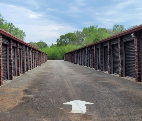 Paved drive between black roll-up storage unit doors and brick columns at StorMark Self Storage on Jefferson Street in Newnan, Georgia