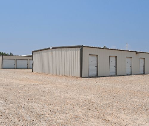Gray storage buildings with white roll-up unit doors at StorMark Self Storage on South 2nd Avenue in Paragould, Arkansas