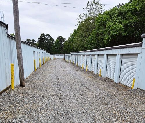 White drive-up storage units with yellow protective bollards at StorMark Self Storage on West Kings Highway in Paragould, Arkansas