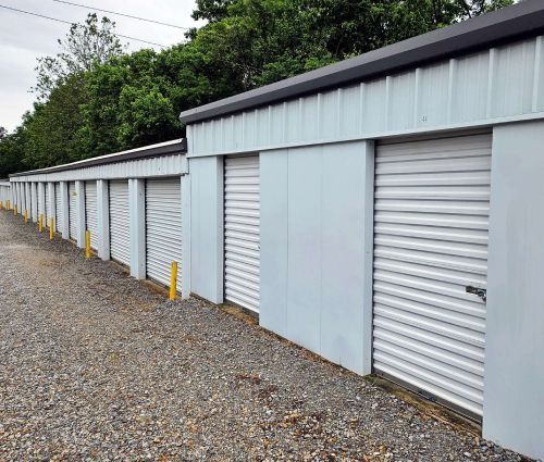 Row of gray drive-up storage unit doors with yellow bollards at StorMark Self Storage on West Kings Highway in Paragould, Arkansas