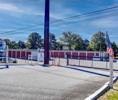 Gated entrance and red roll-up storage unit doors at StorMark Self Storage in Point Harbor, North Carolina