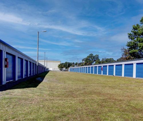 Filas de unidades de almacenamiento azules con acceso para vehículos en un terreno de césped en StorMark Self Storage en Park Drive, Powells Point, Carolina del Norte