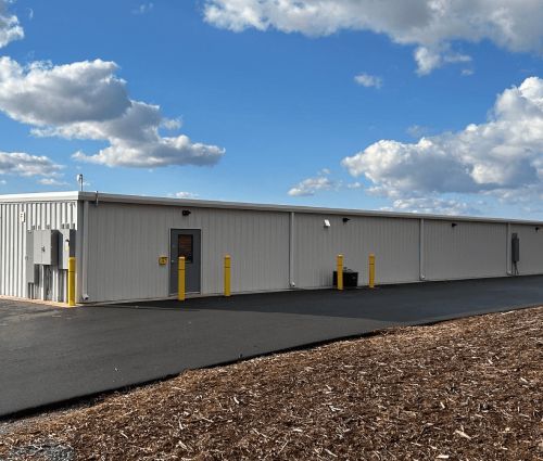 Exterior of a gray metal storage building with yellow protective bollards