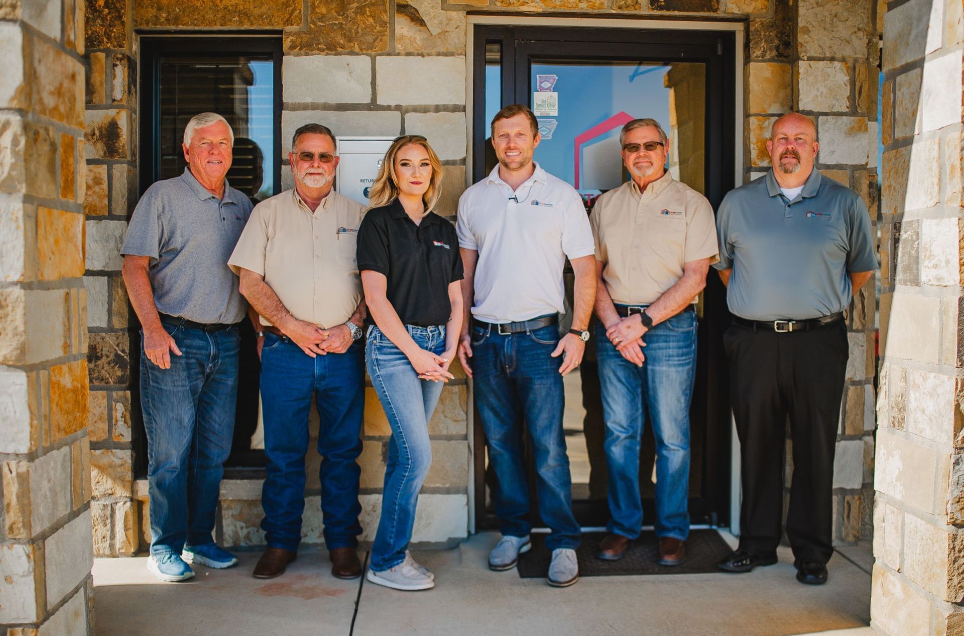Six members of the StorMark team standing together outside a stone office entrance