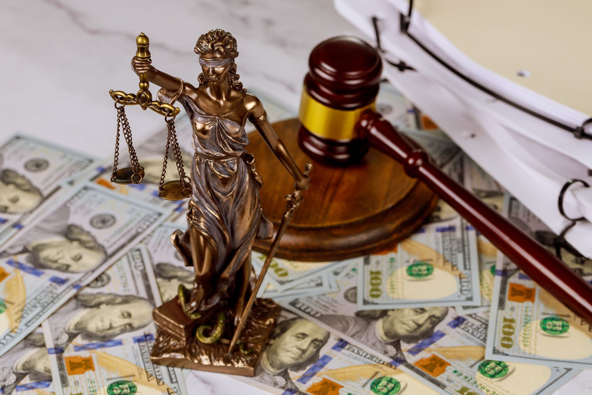 Judge’s gavel and Lady Justice on dollar bills, symbolizing legal finance issues