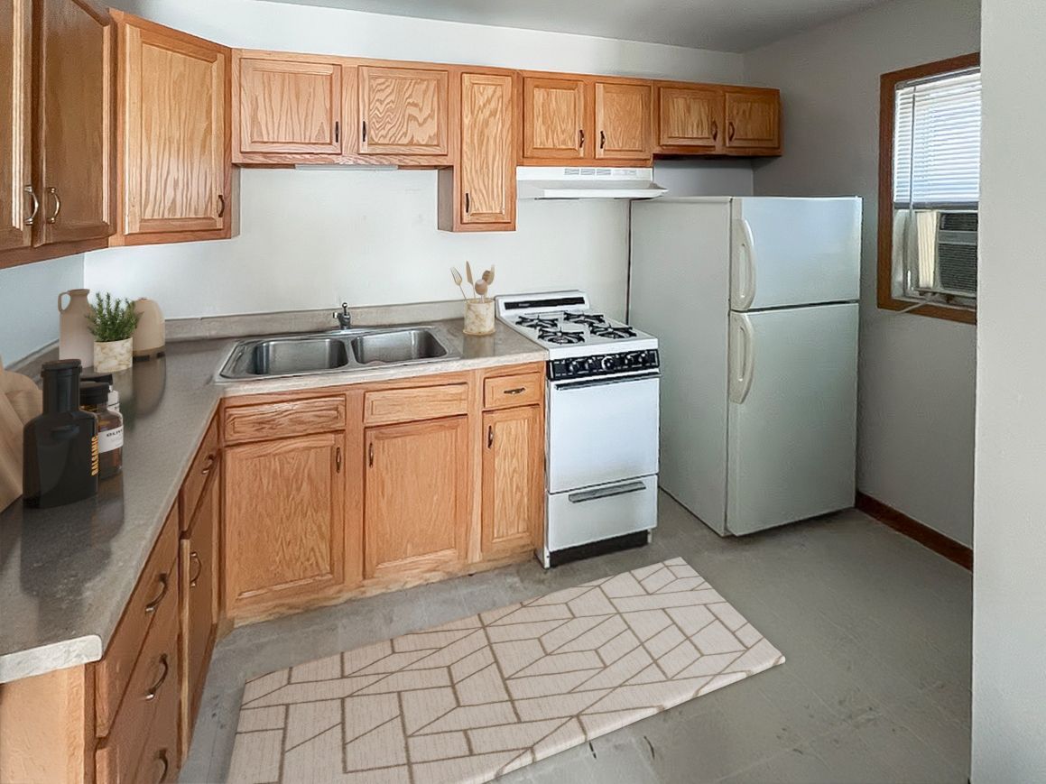 A kitchen with wooden cabinets , a stove , a refrigerator , and a sink.