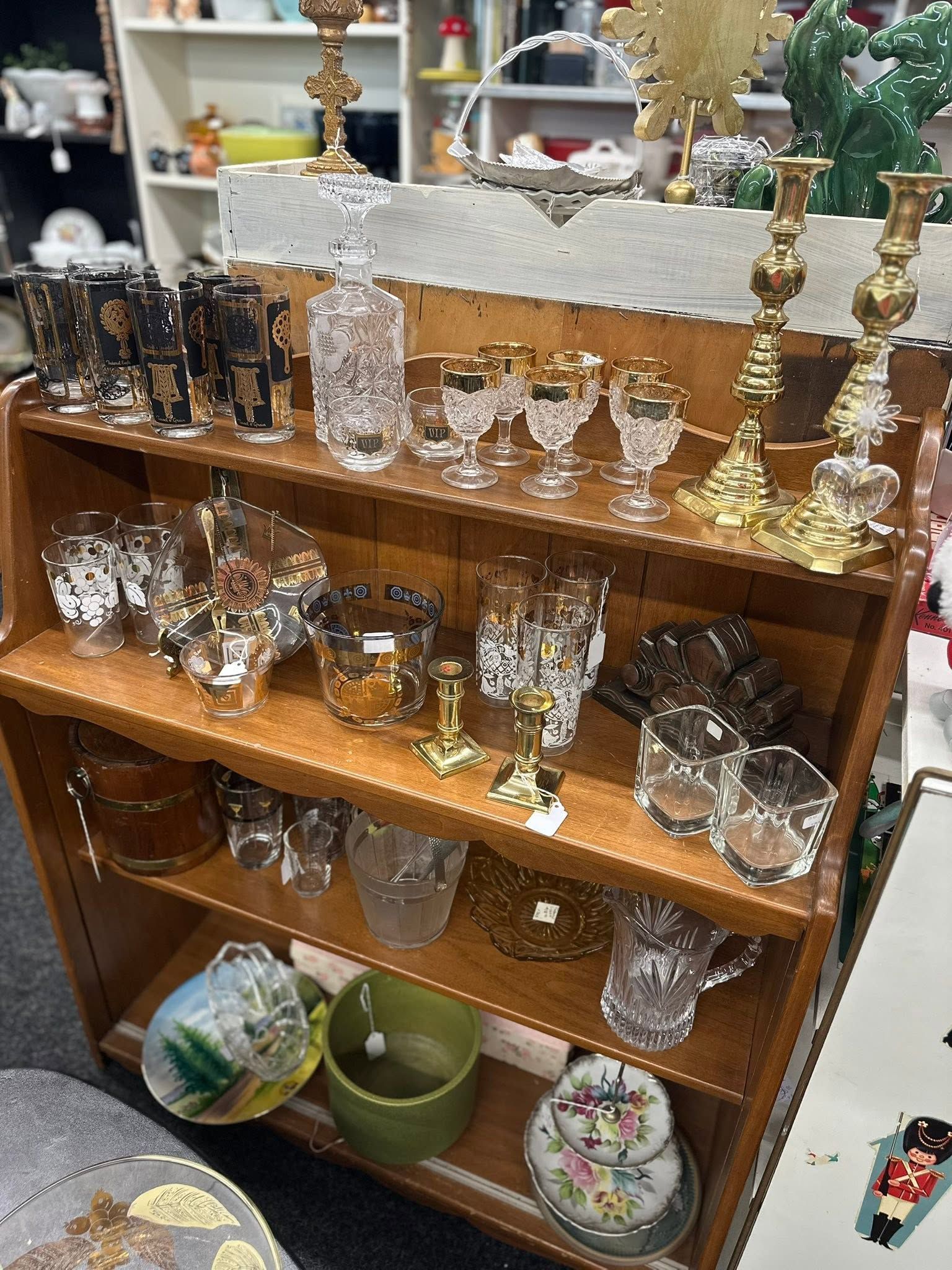 Wooden shelf with assorted glassware and brass candlesticks in a store display