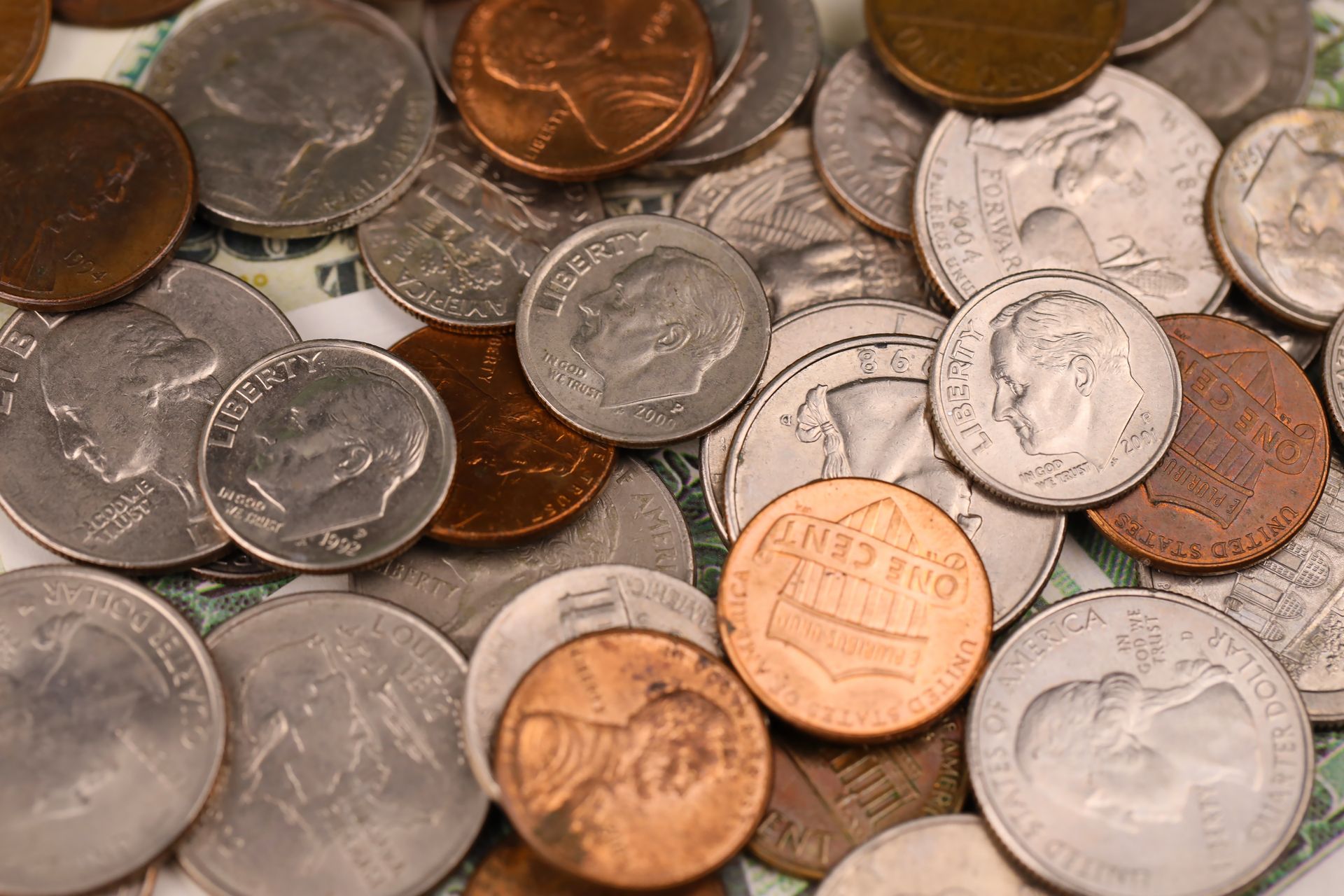 Assorted coins scattered on a wooden tabletop, including copper, silver, and gold tones
