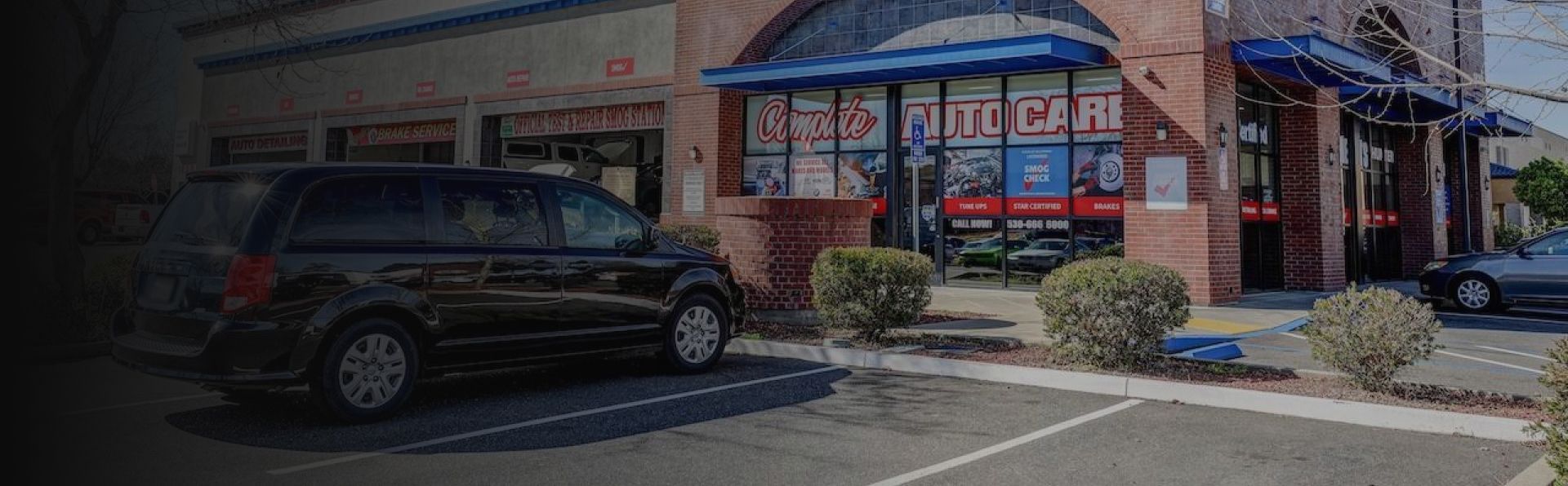 Black SUV parked outside a brick storefront with blue awnings and red window signs | A1 Auto Repair & Detail Center