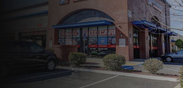 Storefront with blue awning and red window signs on a street corner, with parked cars nearby. | A1 Auto Repair & Detail Center