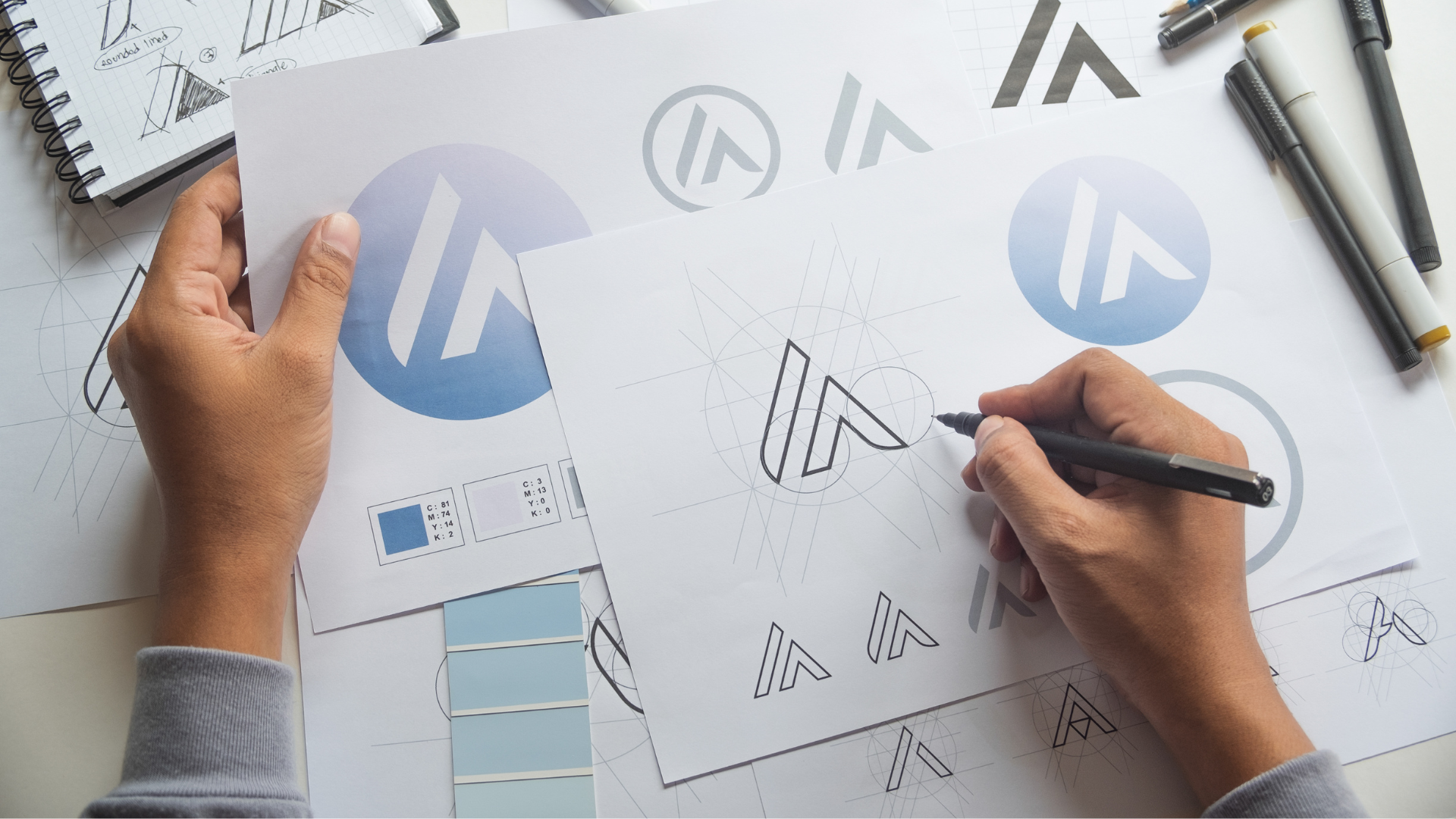 a person is drawing a logo on a piece of paper with a pen .