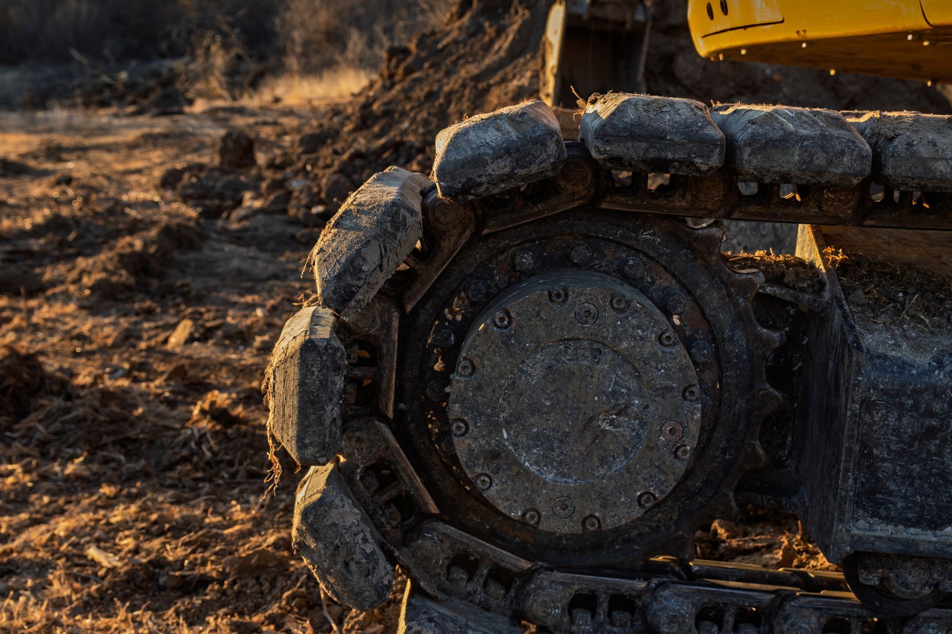 Close-up of a muddy off-road tire on dry, rocky ground at sunset