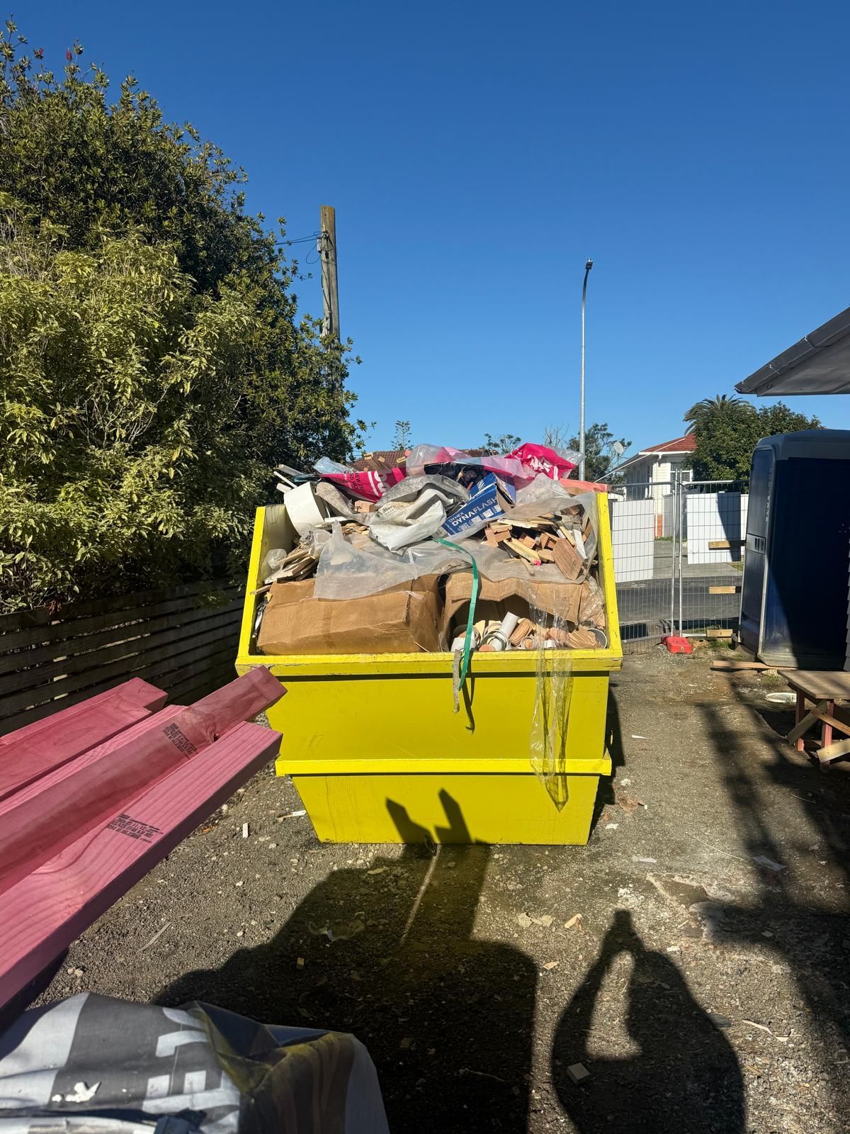 Bright yellow skip bin filled with mixed trash outdoors on a sunny day