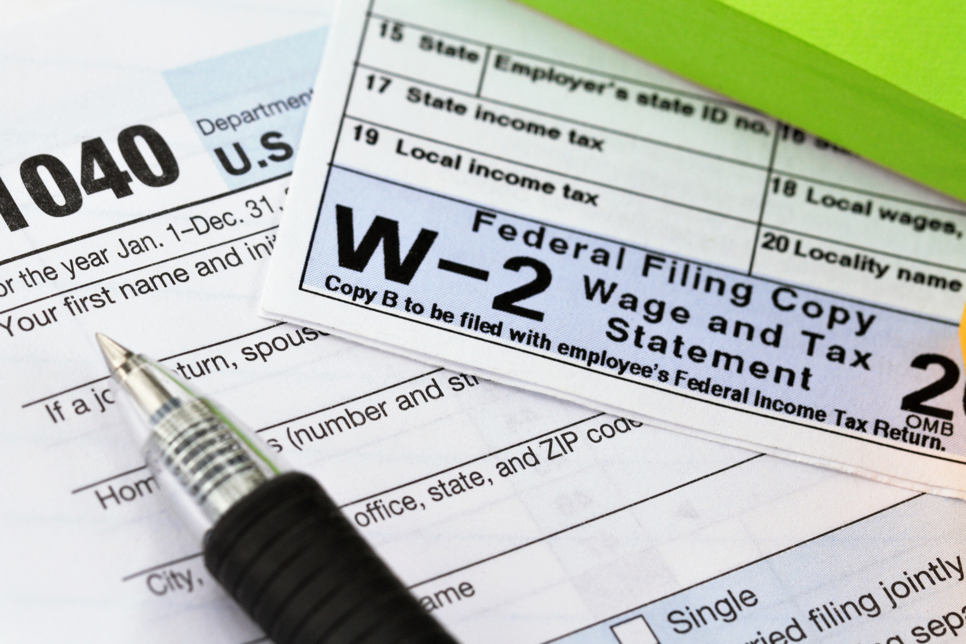 W-2 tax form with pen, surrounded by other tax documents on a desk