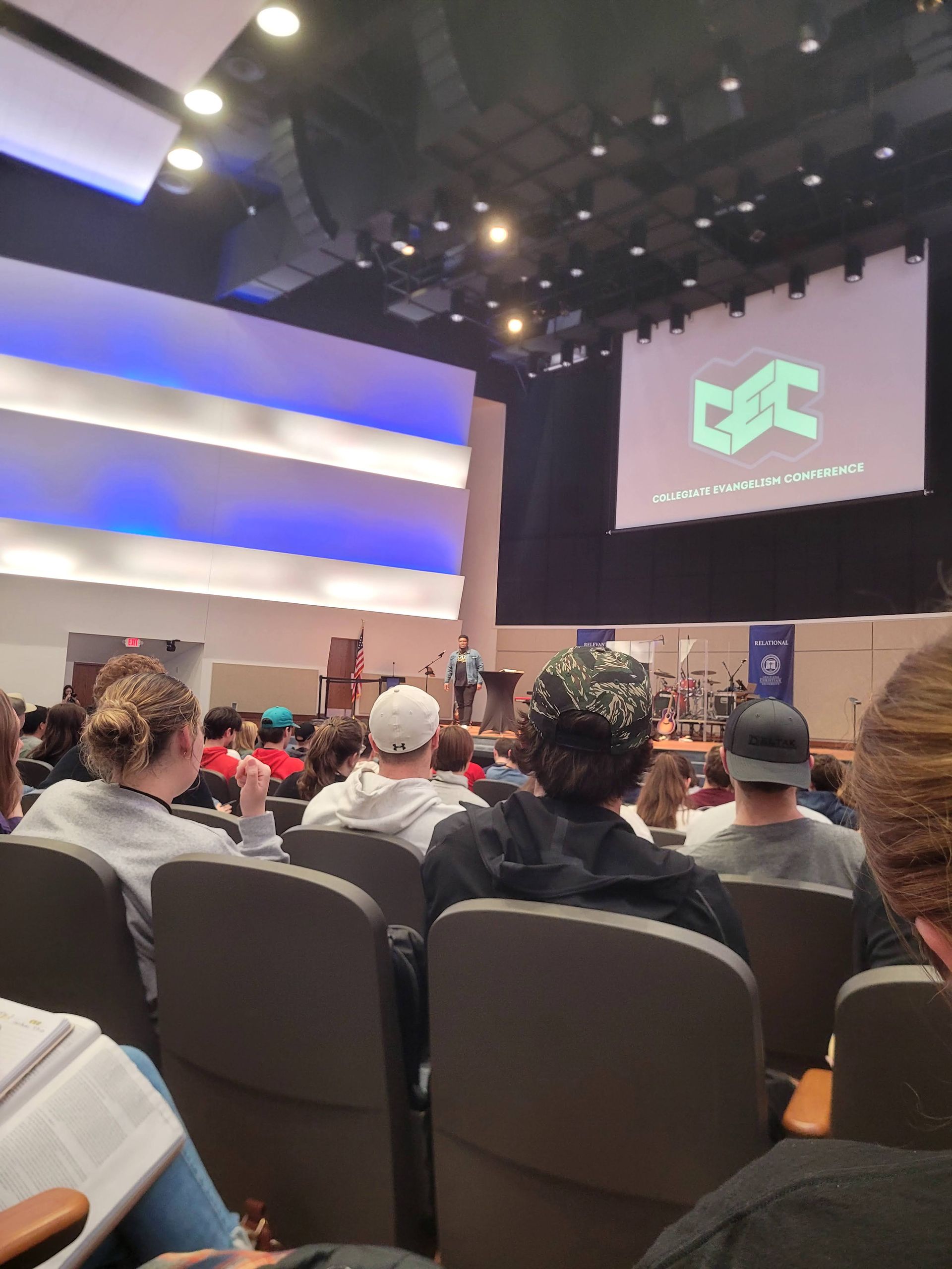 A group of people are sitting in an auditorium watching a presentation