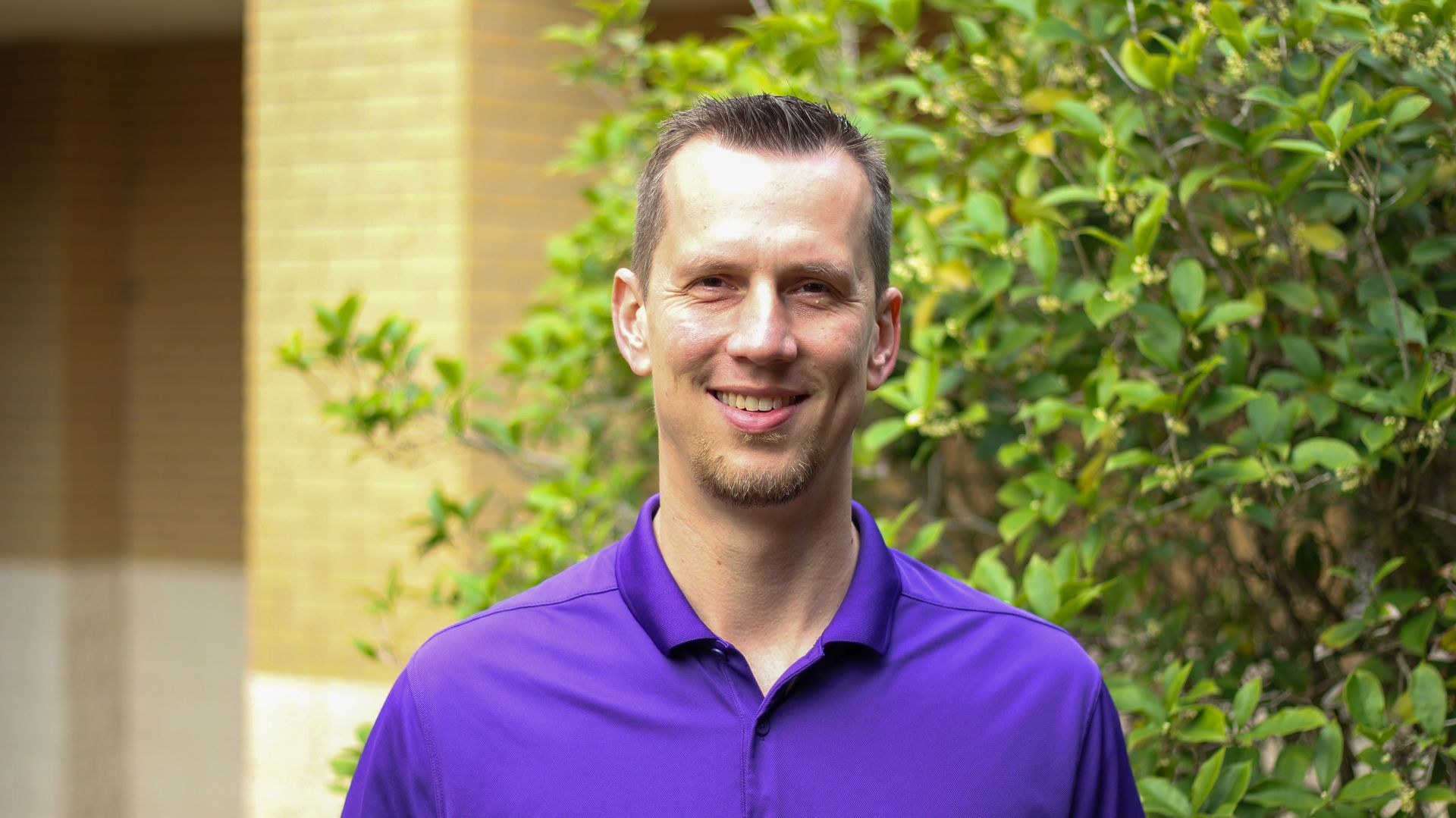 A man in a green shirt is smiling in front of a church.