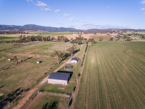 An aerial view of a farm with a barn in the middle of a field.