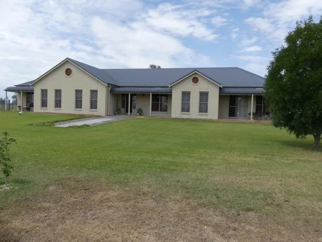 A large house sits in the middle of a lush green field