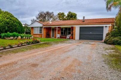 A brick house with a garage and a gravel driveway in front of it.