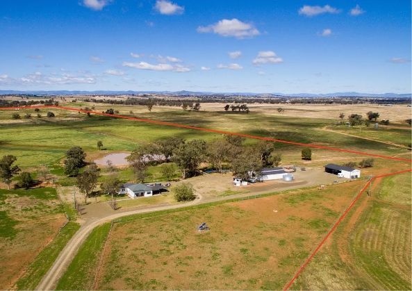 An aerial view of a farm with a house in the middle of a field.