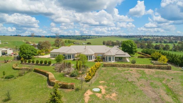 An aerial view of a large house in the middle of a lush green field.