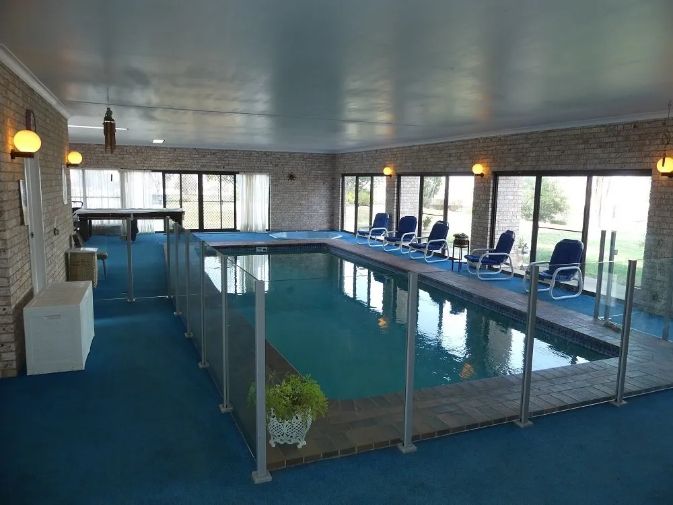 A large indoor swimming pool with chairs and a pool table