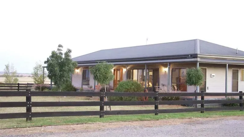 A house with a porch and a wooden fence in front of it.