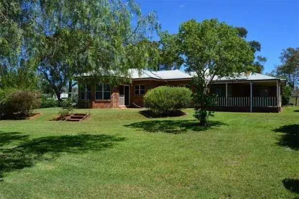 A large house with a porch and trees in front of it.