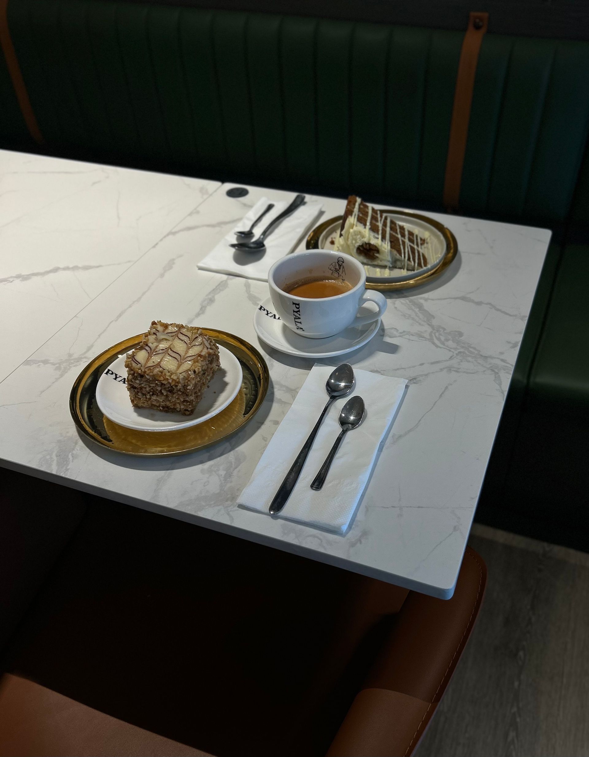 Table with coffee, cake, and silverware, set in a booth.