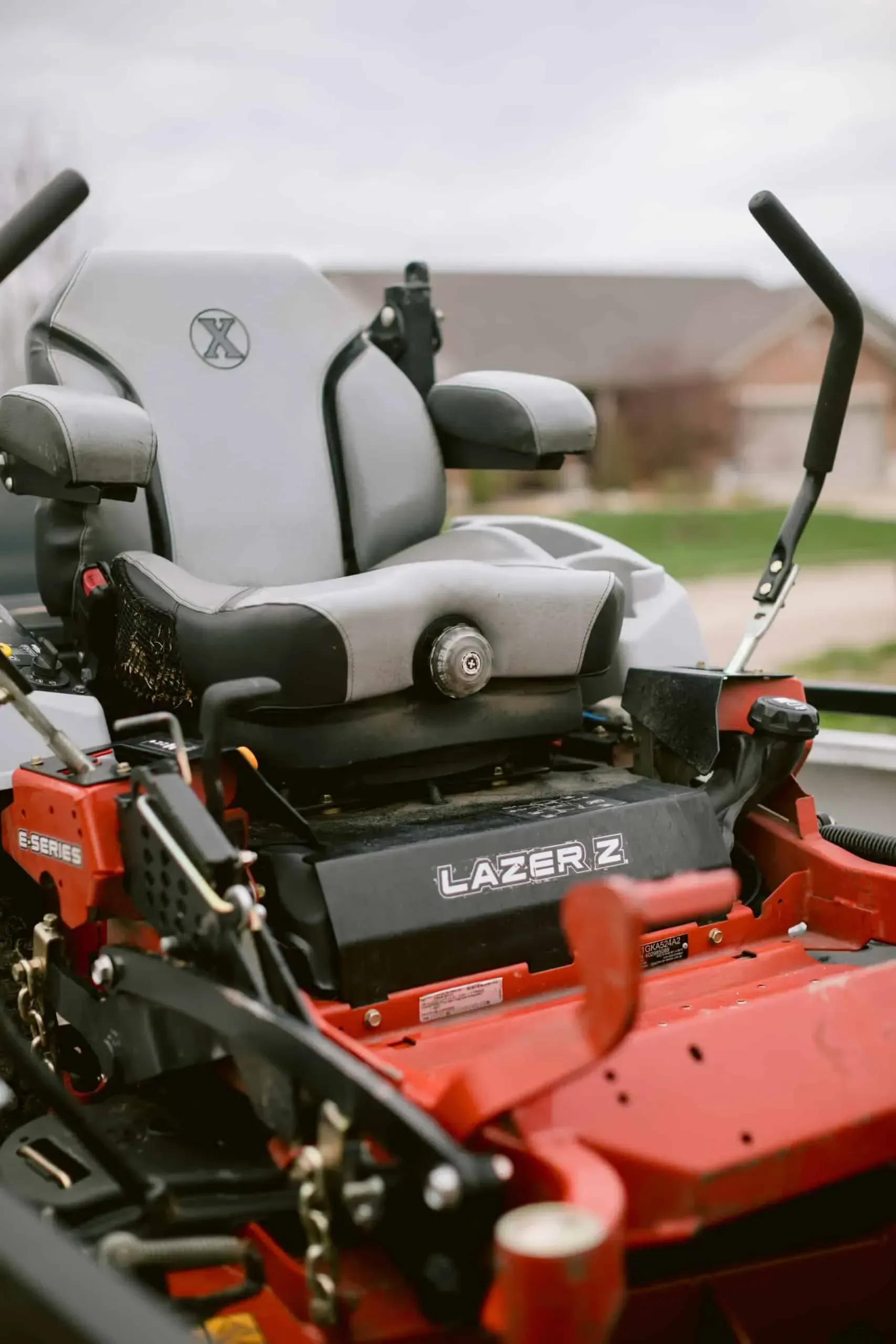 Red and black Exmark Lazer Z zero-turn mower with a gray seat, in an outdoor setting.