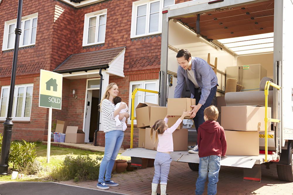 A Family Is Loading Boxes Into A Moving Truck — Romy Sidhu Ray White Weir Views In Melton, VIC