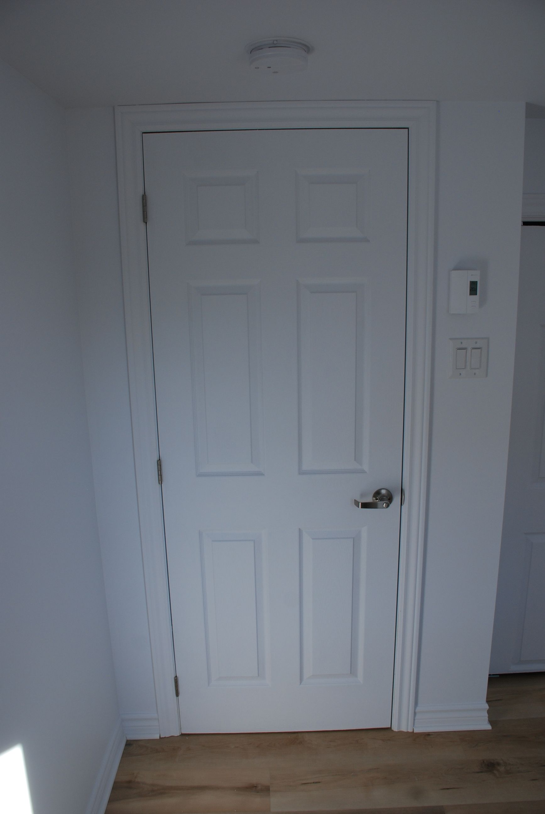 Une porte blanche avec un parquet dans une pièce.