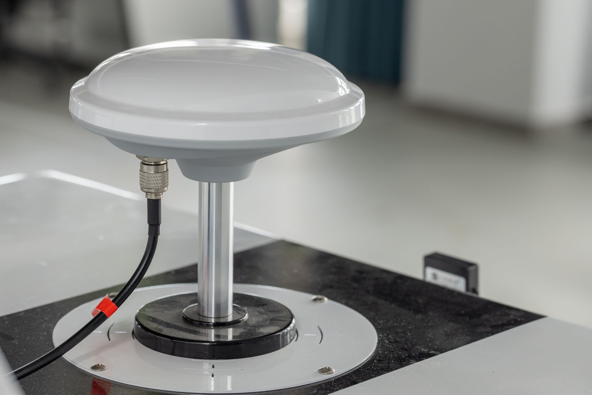 White satellite antenna on a test platform with cables in a lab setting