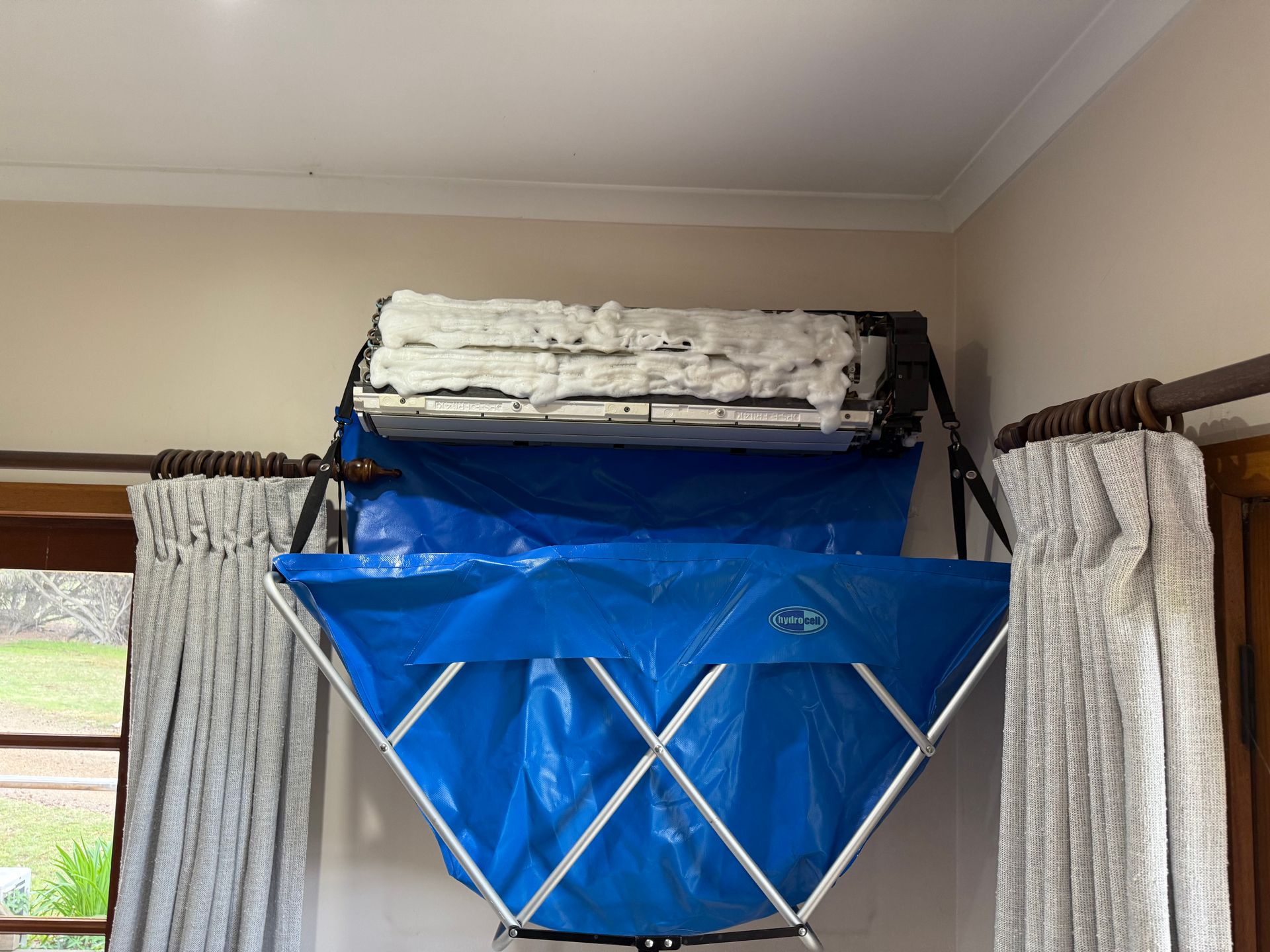Blue lift chair hoisted near a ceiling, between curtains in a room