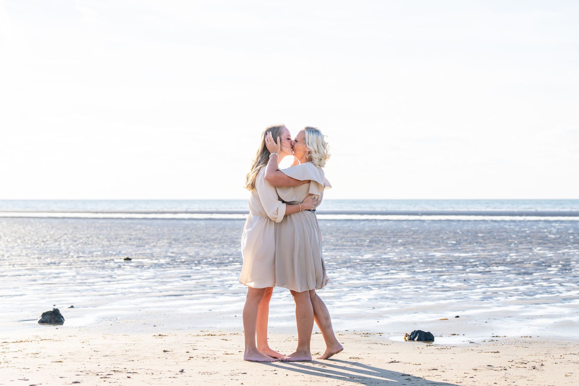 Twee mensen die elkaar omarmen op een zonnig strand aan de oceaan.