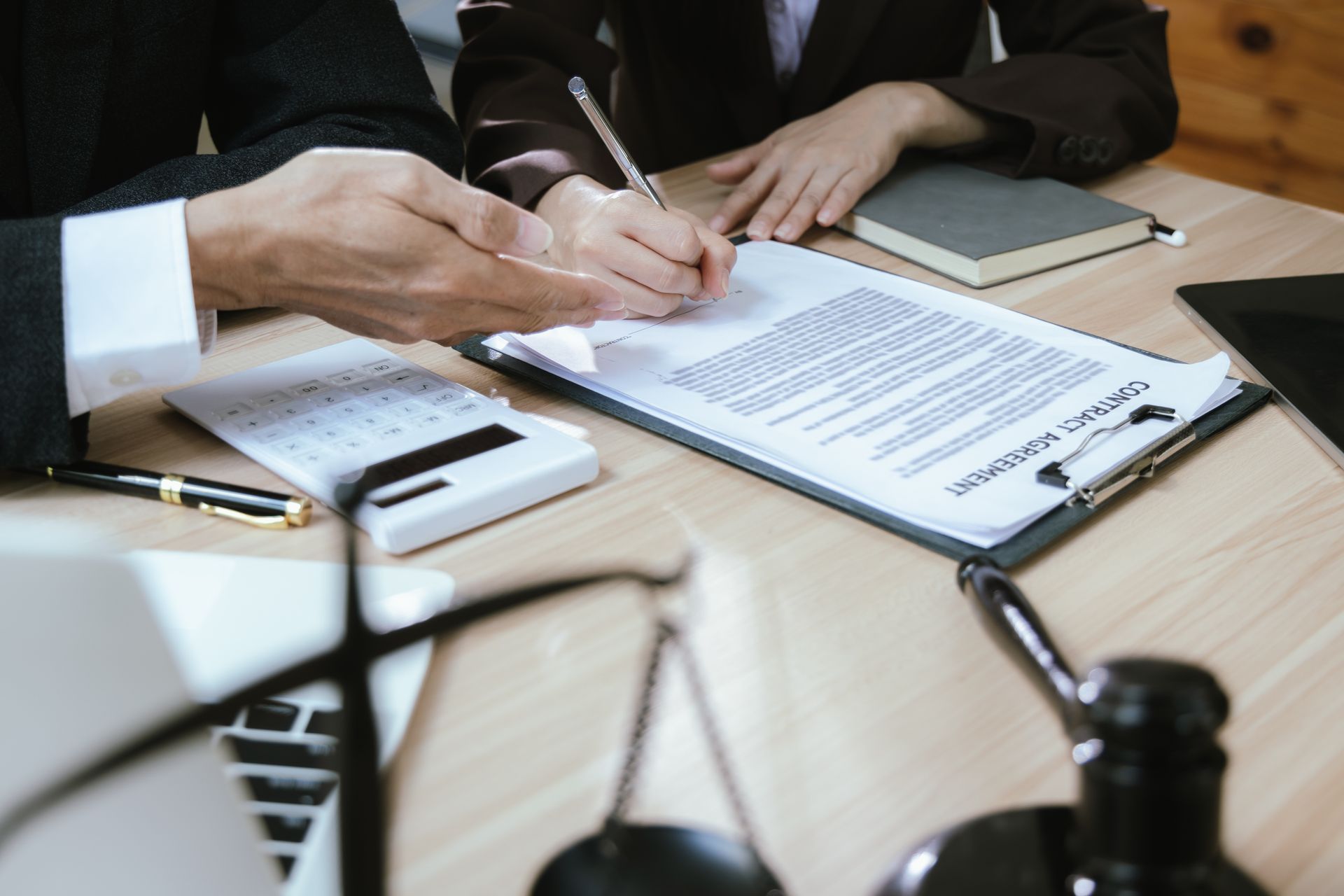 Attorney and client reviewing a personal injury law contract agreement with gavel and scales nearby