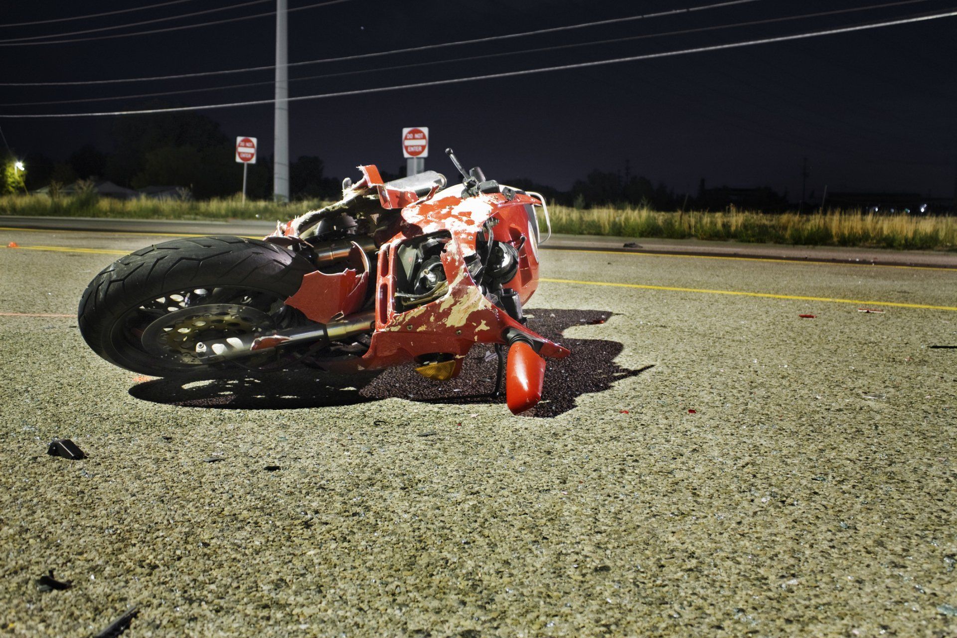 Damaged red motorcycle lying on road at night after accident.