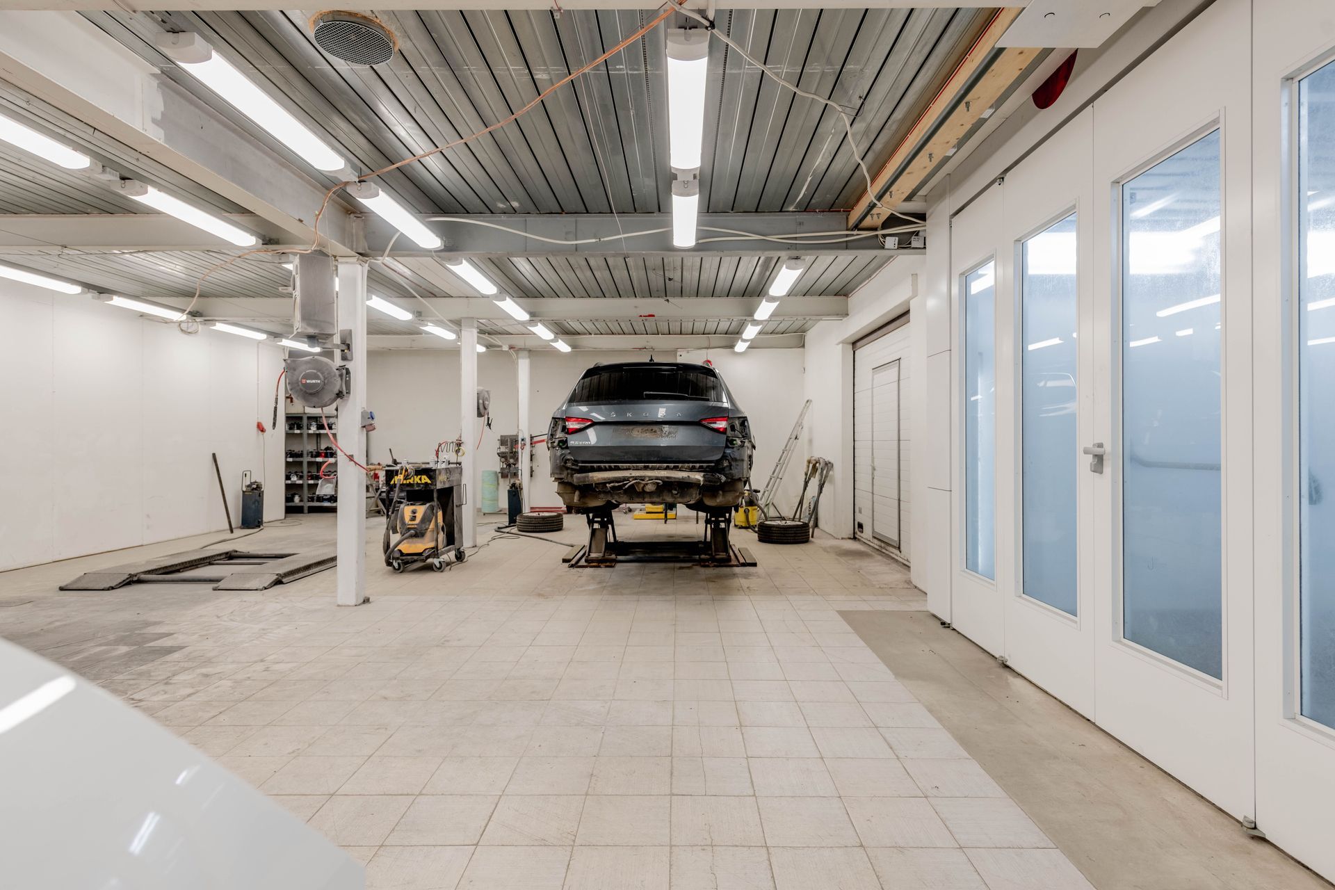 Black SUV in a bright auto detailing bay with tiled floor and white walls