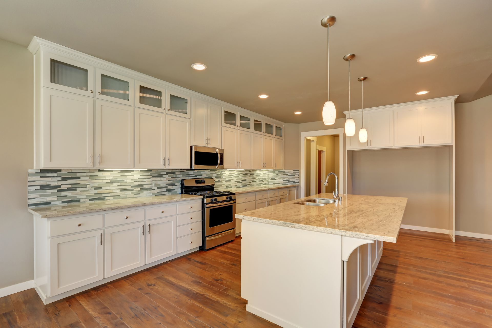 Bright modern kitchen with white cabinets, granite island, stainless appliances, and hardwood floors