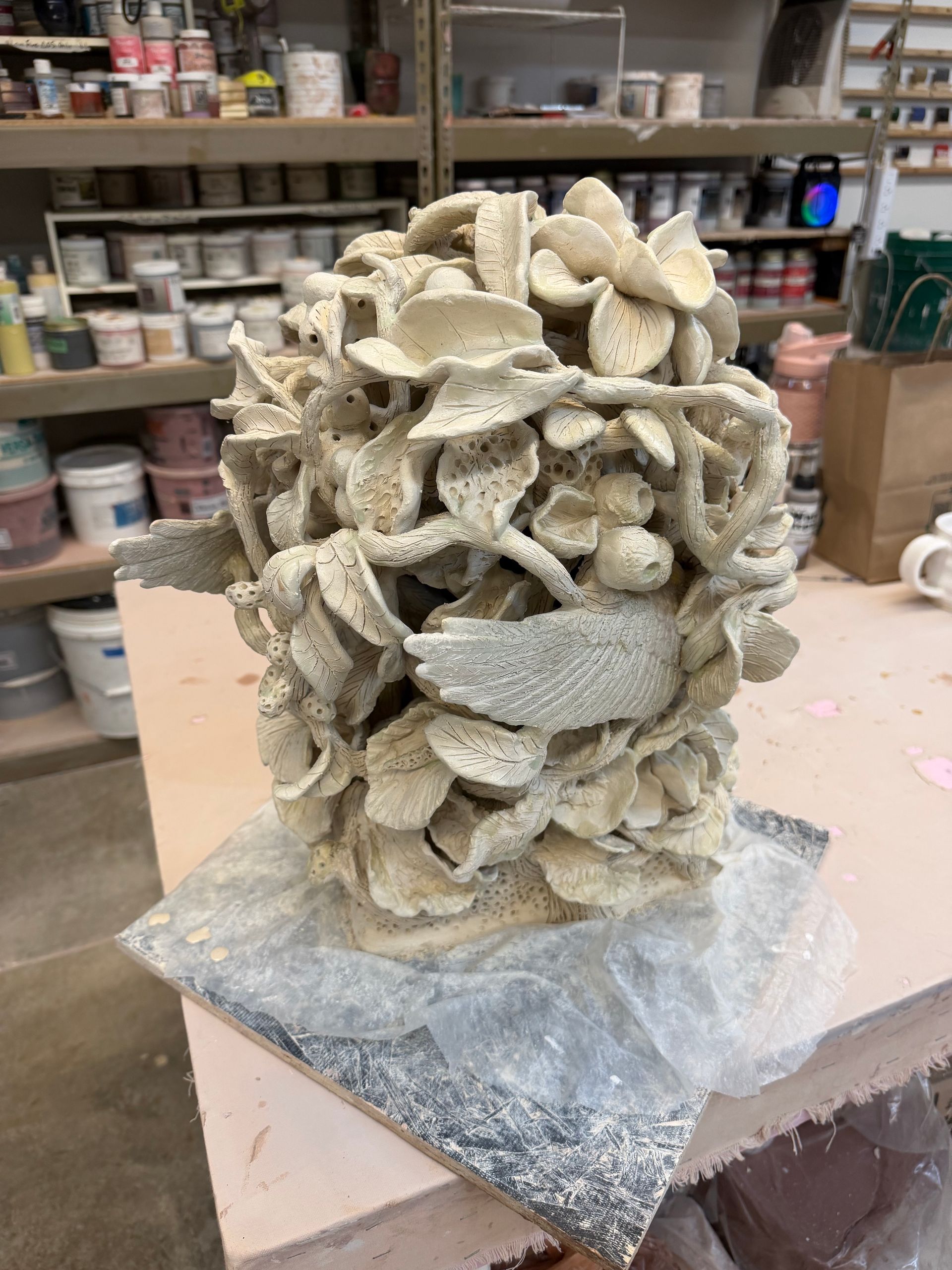 Pale seashell-encrusted decorative sculpture on a worktable in a studio or craft shop