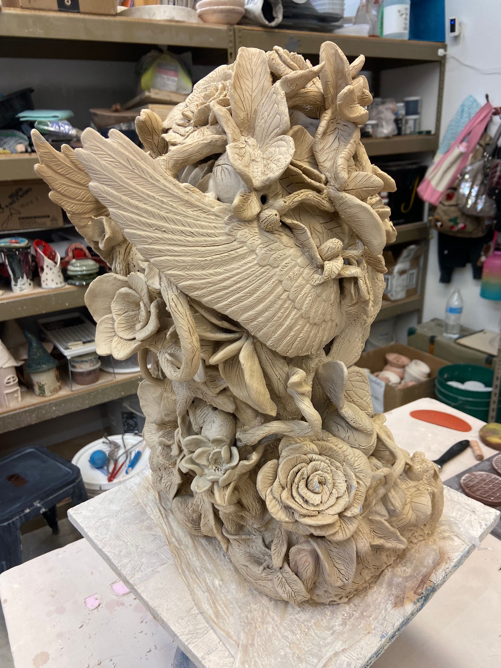 Handcrafted beige sculpture of flowers and leaves on a square base in a studio workspace