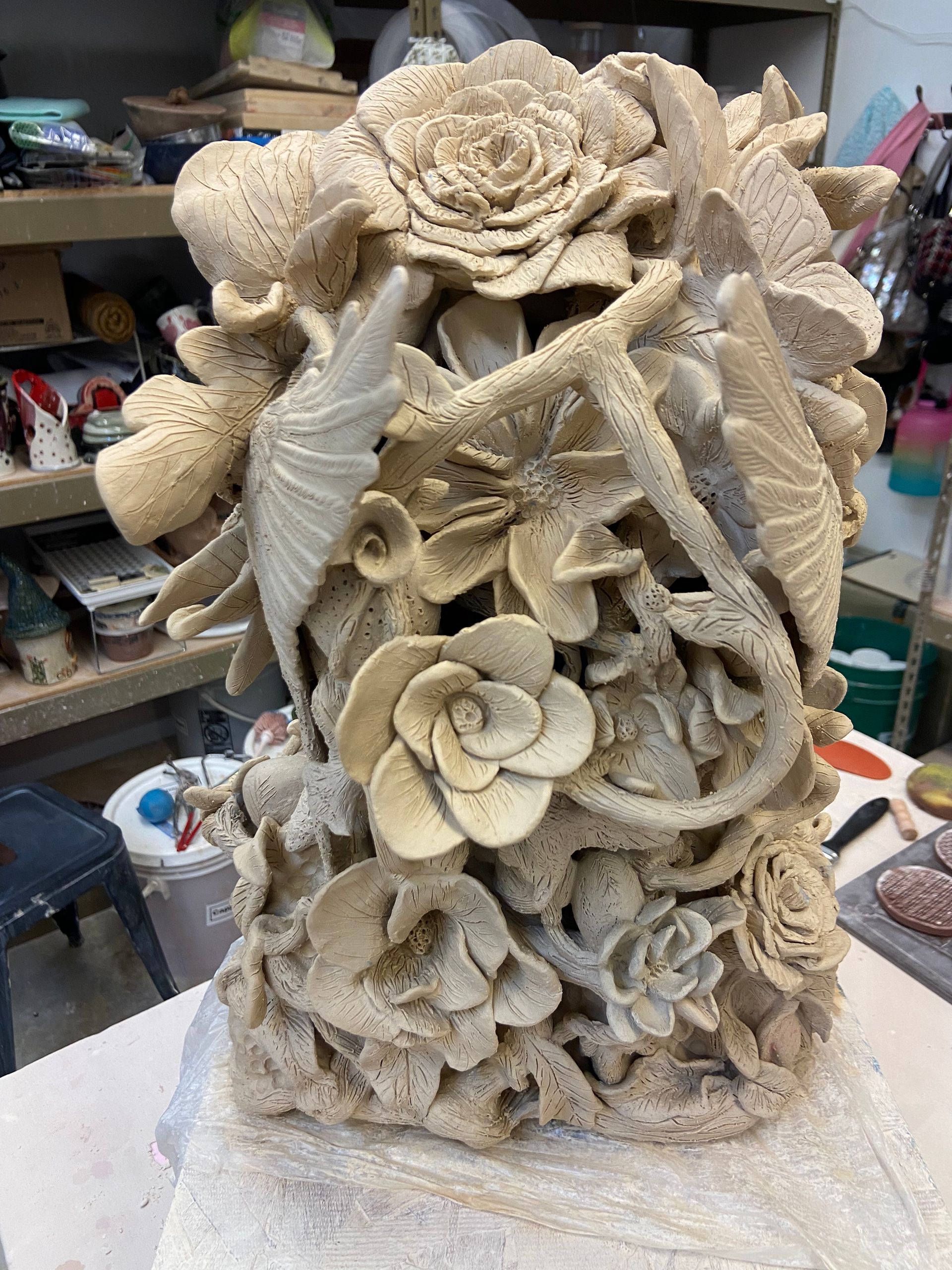 Beige sculptural floral relief with roses and leaves on a workshop table